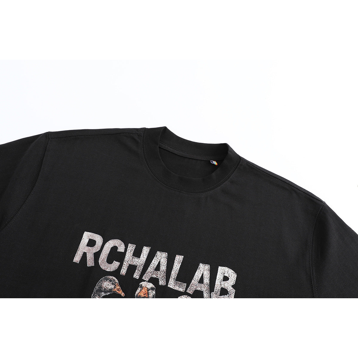 Close-up of a black crew-neck T-shirt showing part of its RCHALAB bird graphic.