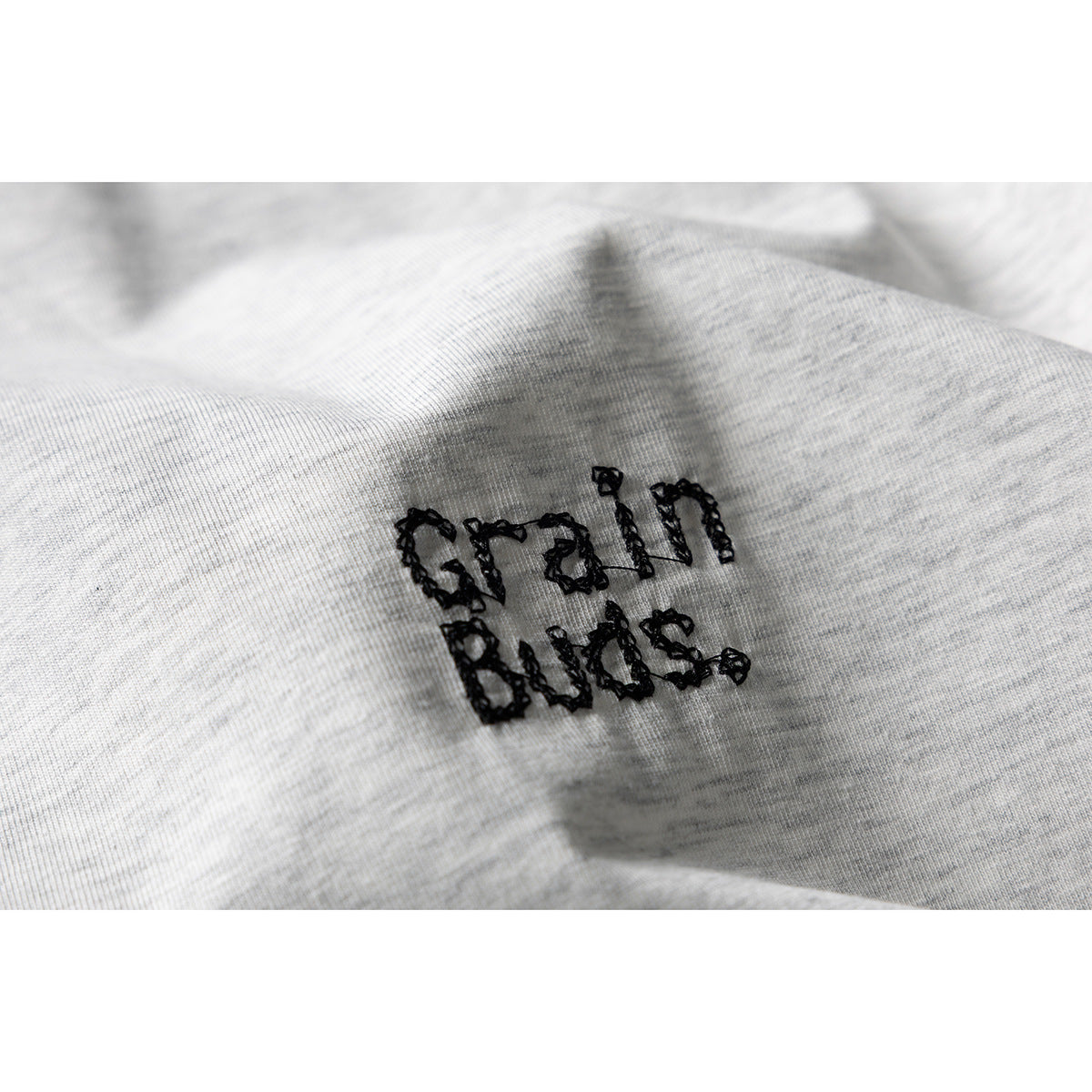 Close-up of black embroidered lettering on light gray melange T-shirt fabric.