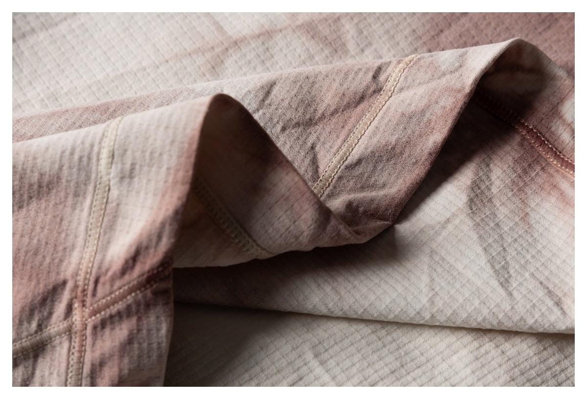 Close-up of folded shirt fabric showing a stitched edge and the beige and brown mottled pattern.