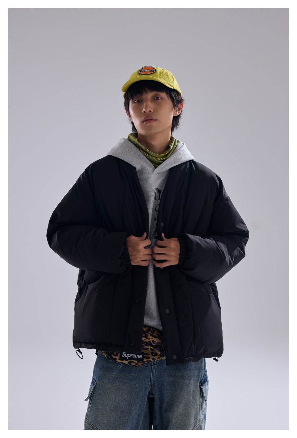 Front view of a model wearing an oversized black quilted jacket with snap closures and a gathered hem.