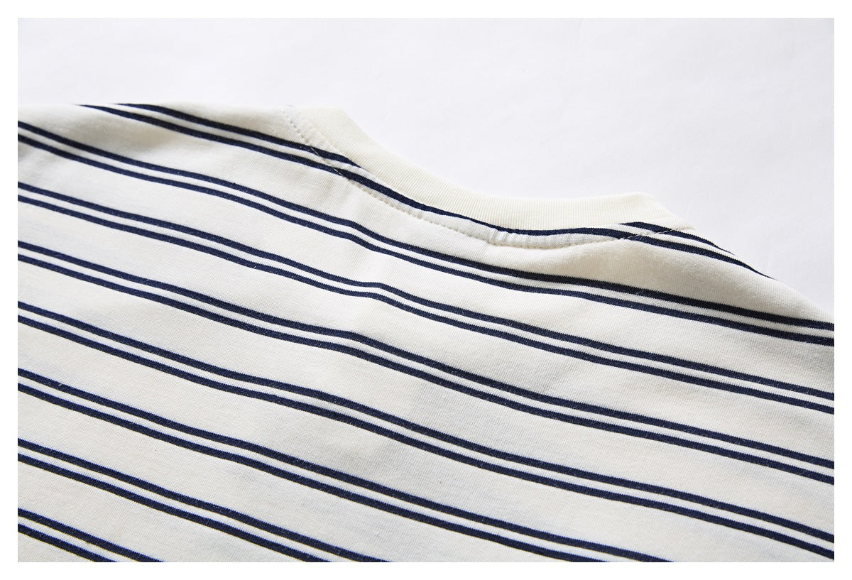 Close-up of the neckline and shoulder of an ivory garment with dark navy stripes.