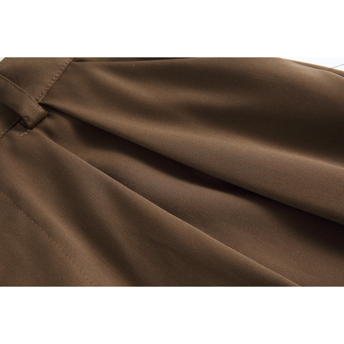 Close-up of brown shorts fabric folded to show its texture, drape and stitching.