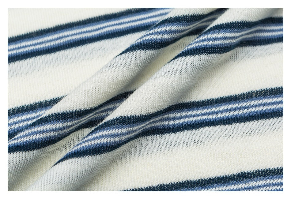 Close-up of ivory knit fabric with navy and pale blue stripes, loosely draped to show its texture.