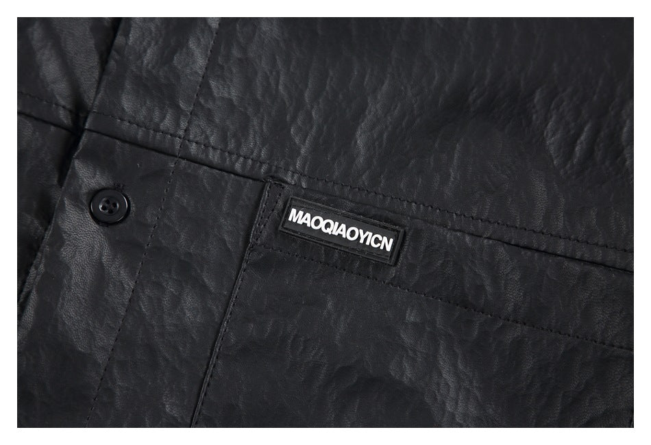 Close-up of the black shirt’s chest pocket seam, button, and small brand patch.