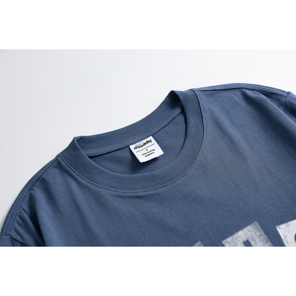 Close-up of a slate-blue T-shirt crew neck, stitching, and sewn-in label.