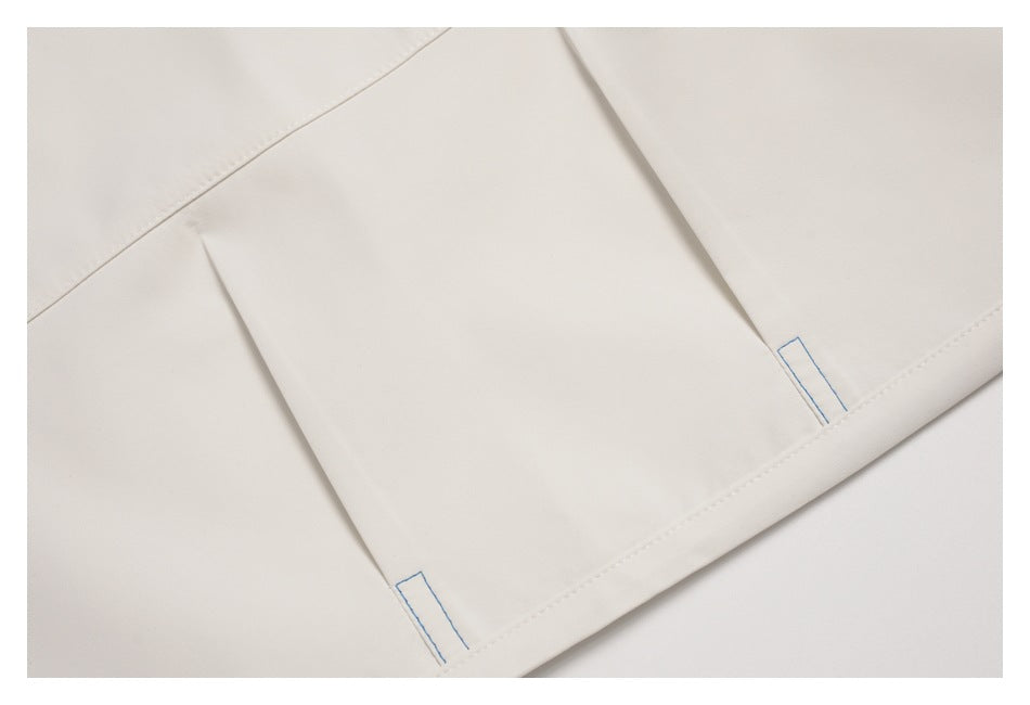 Close-up of a white pant section showing a folded seam and blue stitching near the hem.
