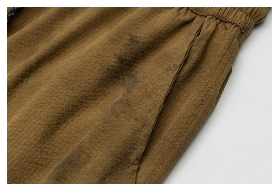 Close-up of brown shorts showing a side pocket opening, stitching, and gathered elastic waistband.