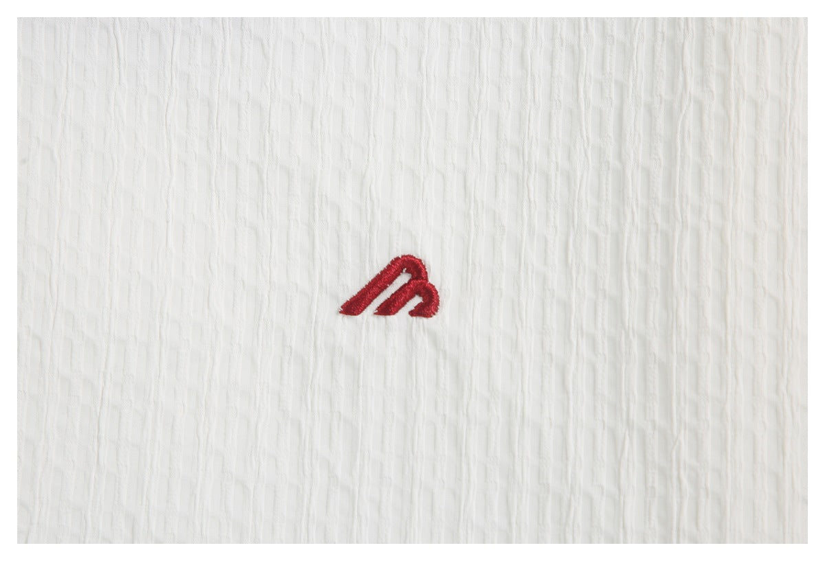 Small red embroidered emblem on white textured shirt fabric.