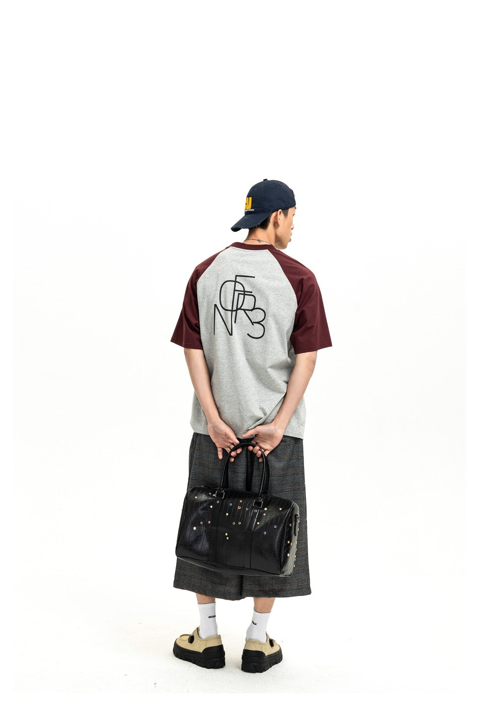 Back view of a model wearing a gray T-shirt with burgundy raglan sleeves and a large black back graphic.