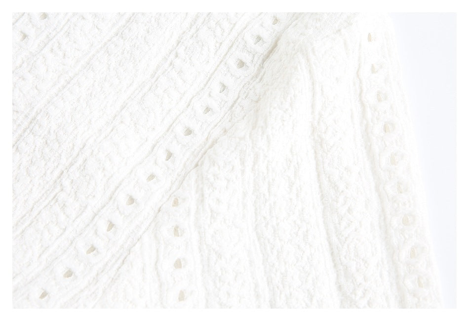 Close-up of white textured fabric with decorative rows of small openwork details.