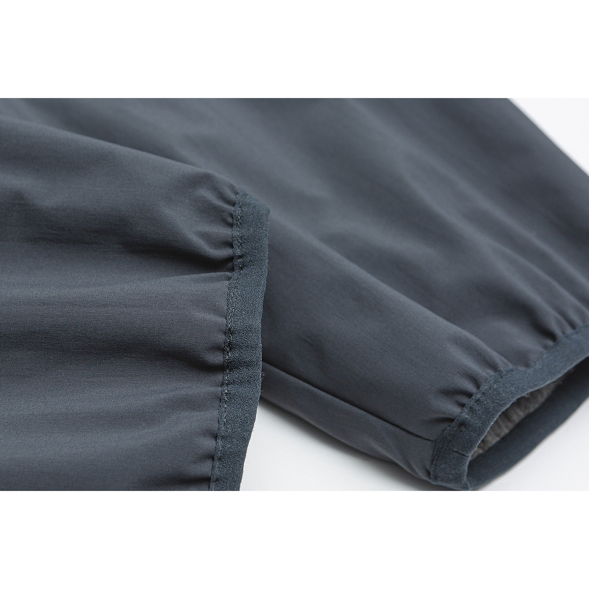 Close-up of a dark gray jacket sleeve and cuff, showing gathered fabric and dark trim.
