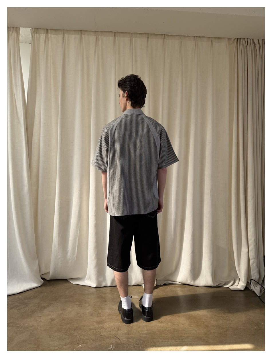 Back view of model wearing the gray striped short-sleeve shirt with raglan sleeves and black shorts
