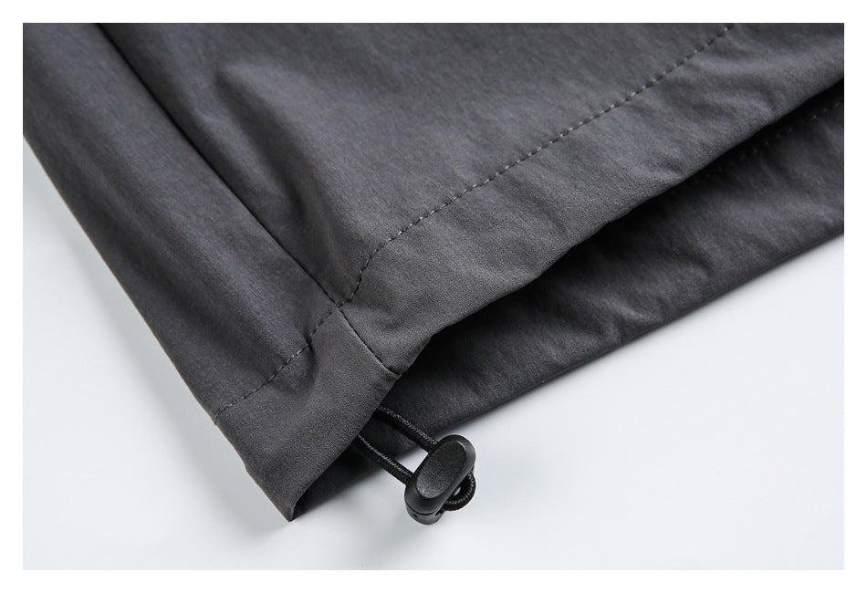 Close-up of a charcoal-gray garment hem with a black drawcord and toggle.
