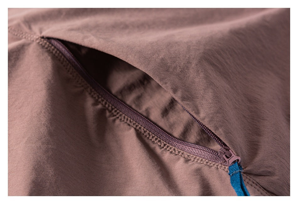 Close-up of a mauve garment with an open zipper and blue fabric pull tab.