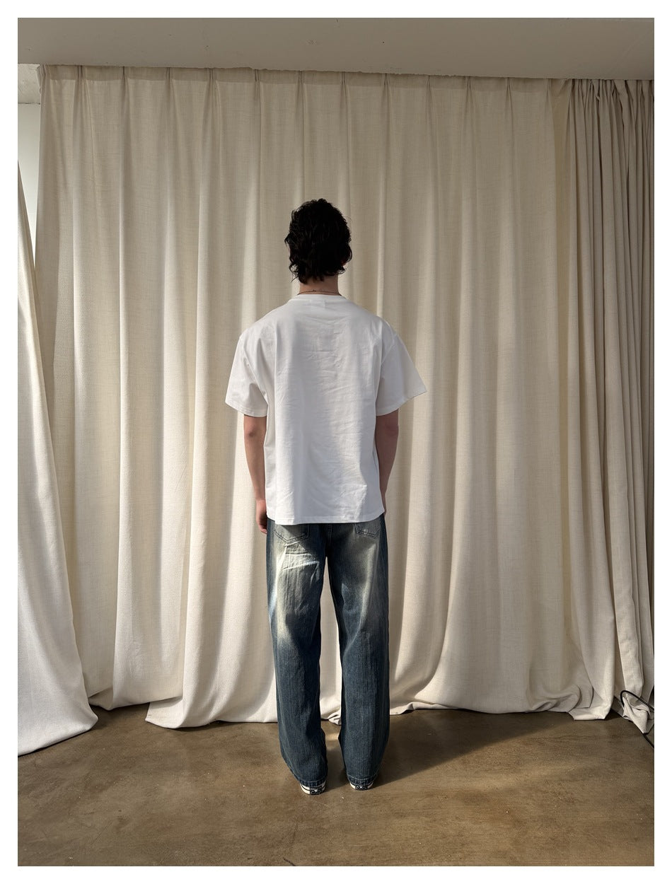 Back view of a model wearing a plain white short-sleeve T-shirt with loose faded jeans.