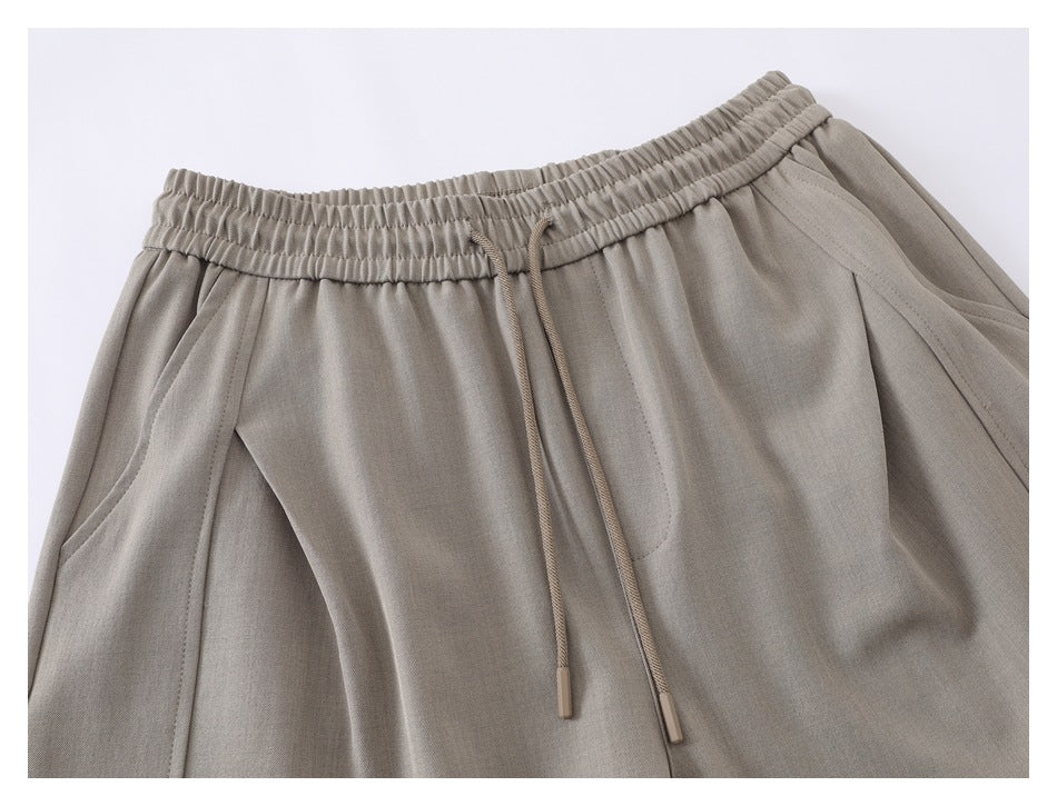 Close-up of taupe shorts showing the elastic drawstring waistband and curved front pockets.