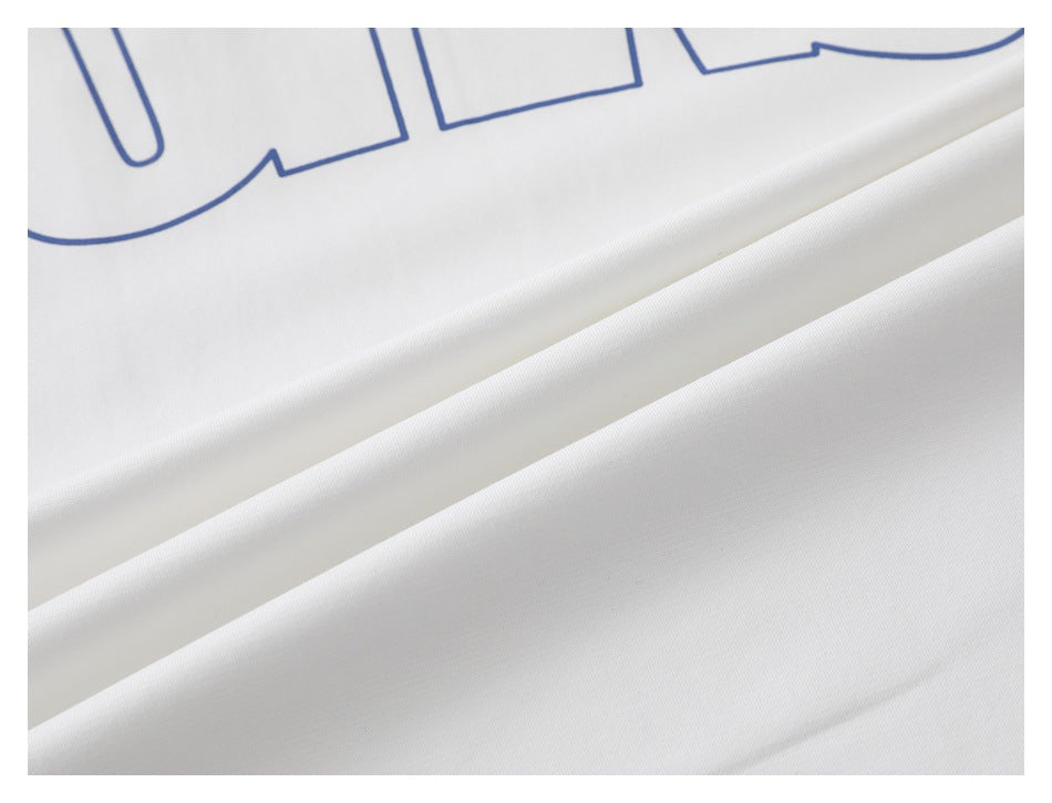 Close-up of white shirt fabric draped in folds, with part of a large blue outlined print visible.