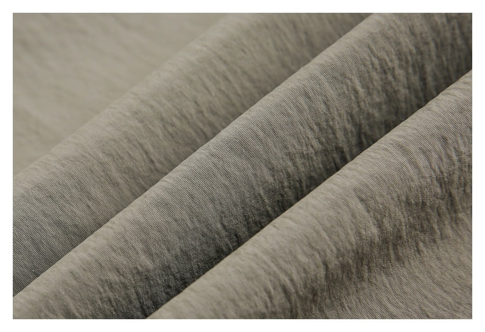 Macro close-up showing the fine woven texture and folds of olive-gray fabric.