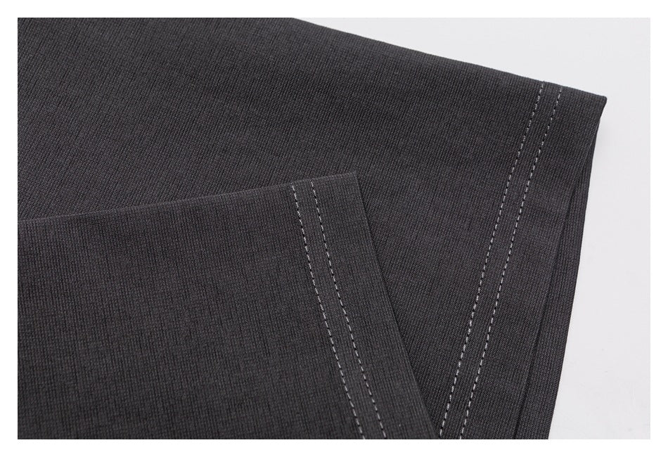 Close-up of dark garment fabric with parallel rows of light stitching along a folded edge.