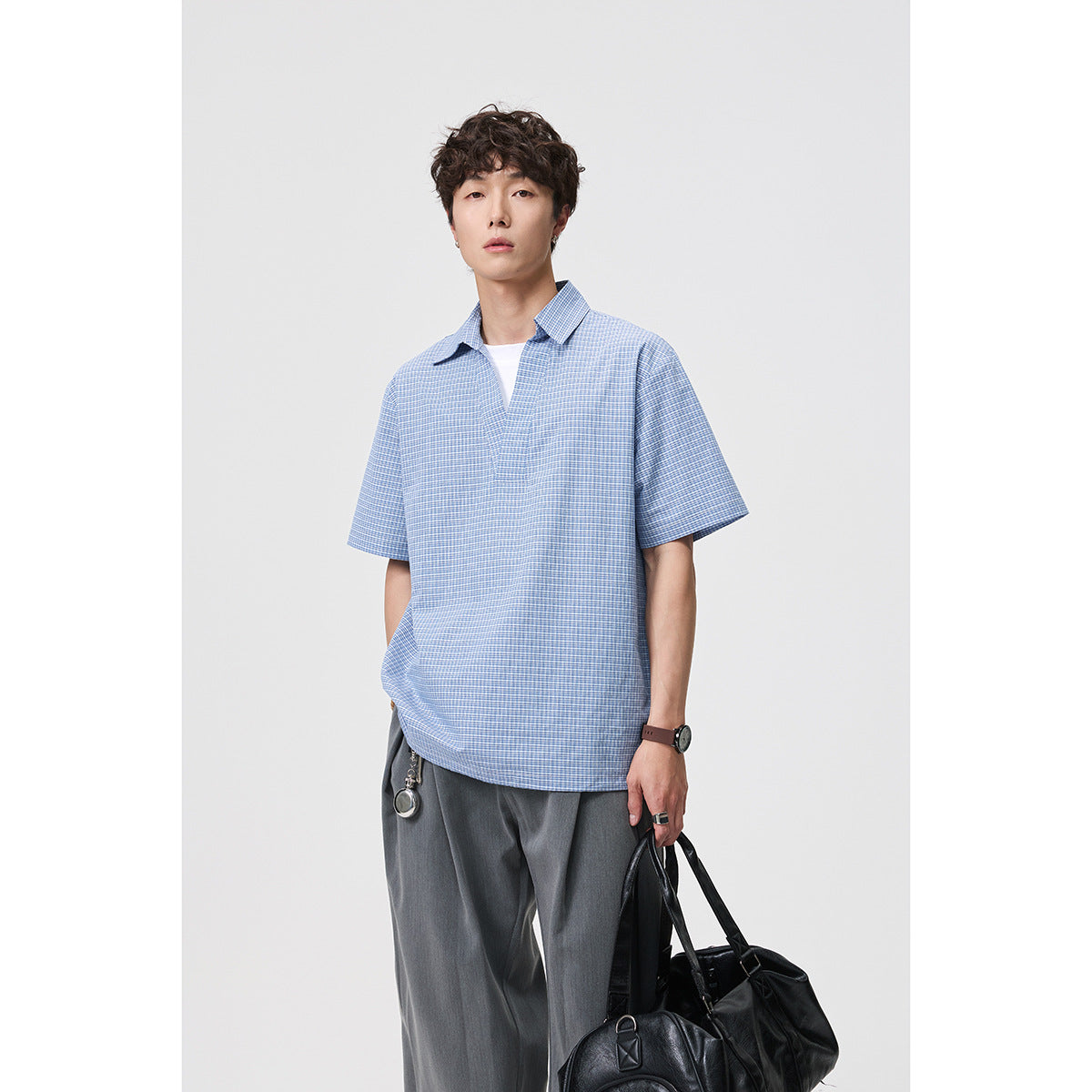 Front view of a man modeling a blue-and-white micro-check short-sleeve collared shirt.