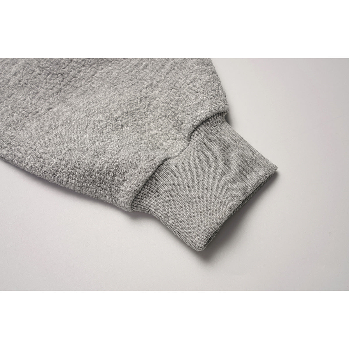 Close-up of the gray textured sweatshirt sleeve and ribbed cuff.