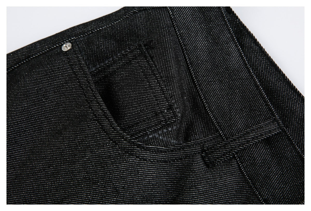 Close-up of a stitched rear pocket and waistband on black jeans.