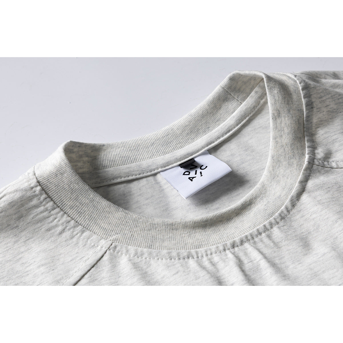 Close-up of a light gray melange T-shirt's ribbed crew neck and inner white label.