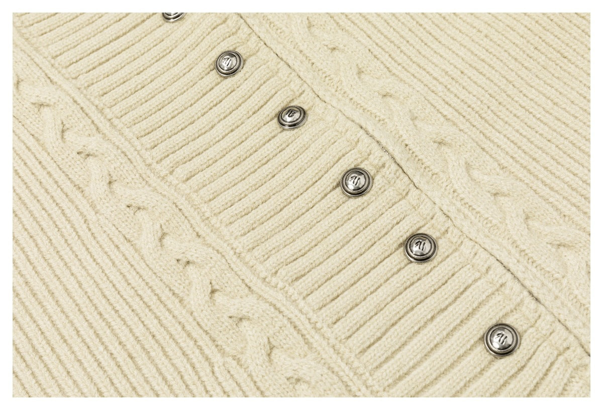 Close-up of the ivory cable-knit cardigan's ribbed button placket and round metallic buttons.