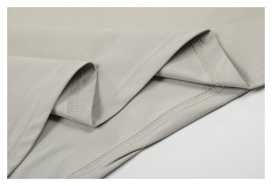 Close-up of the light beige garment's folded hem and overlocked interior seams.