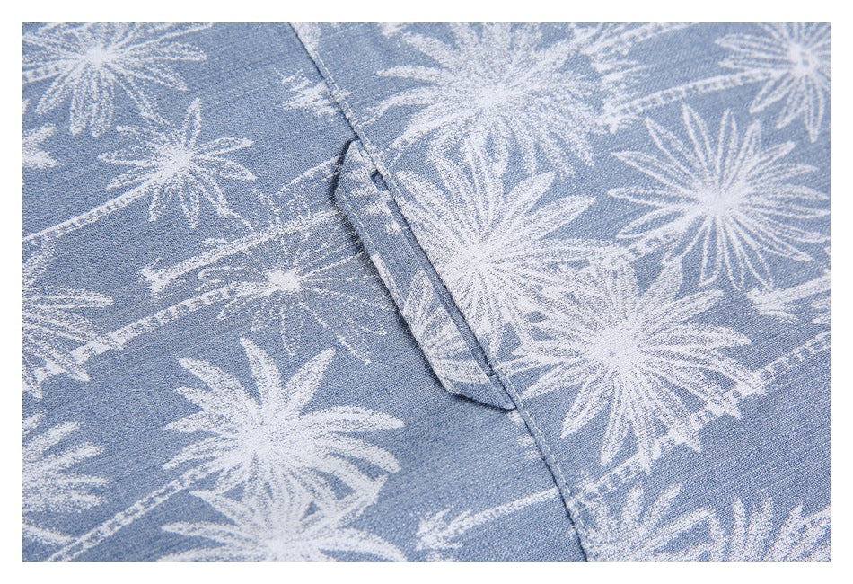 Close-up of a stitched pocket edge on light blue fabric with a white palm-tree print.