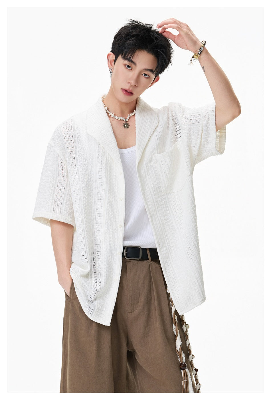 Model in a white openwork short-sleeve button-up shirt with shawl collar and chest pocket, shown from the front.