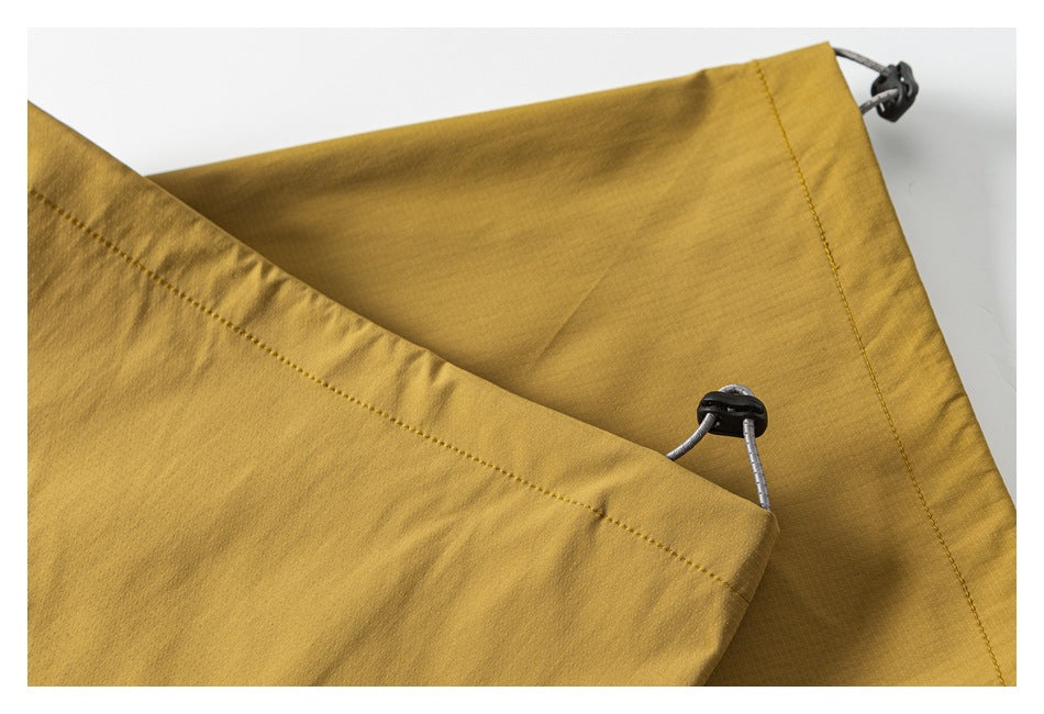 Close-up of mustard-gold trousers showing the waistband and adjustable drawcord toggles.