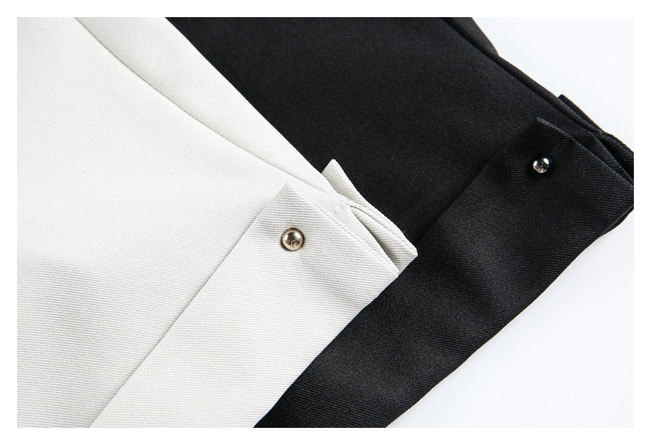 Close-up of the white and black tunics' cuff tabs with shiny metal snap buttons.
