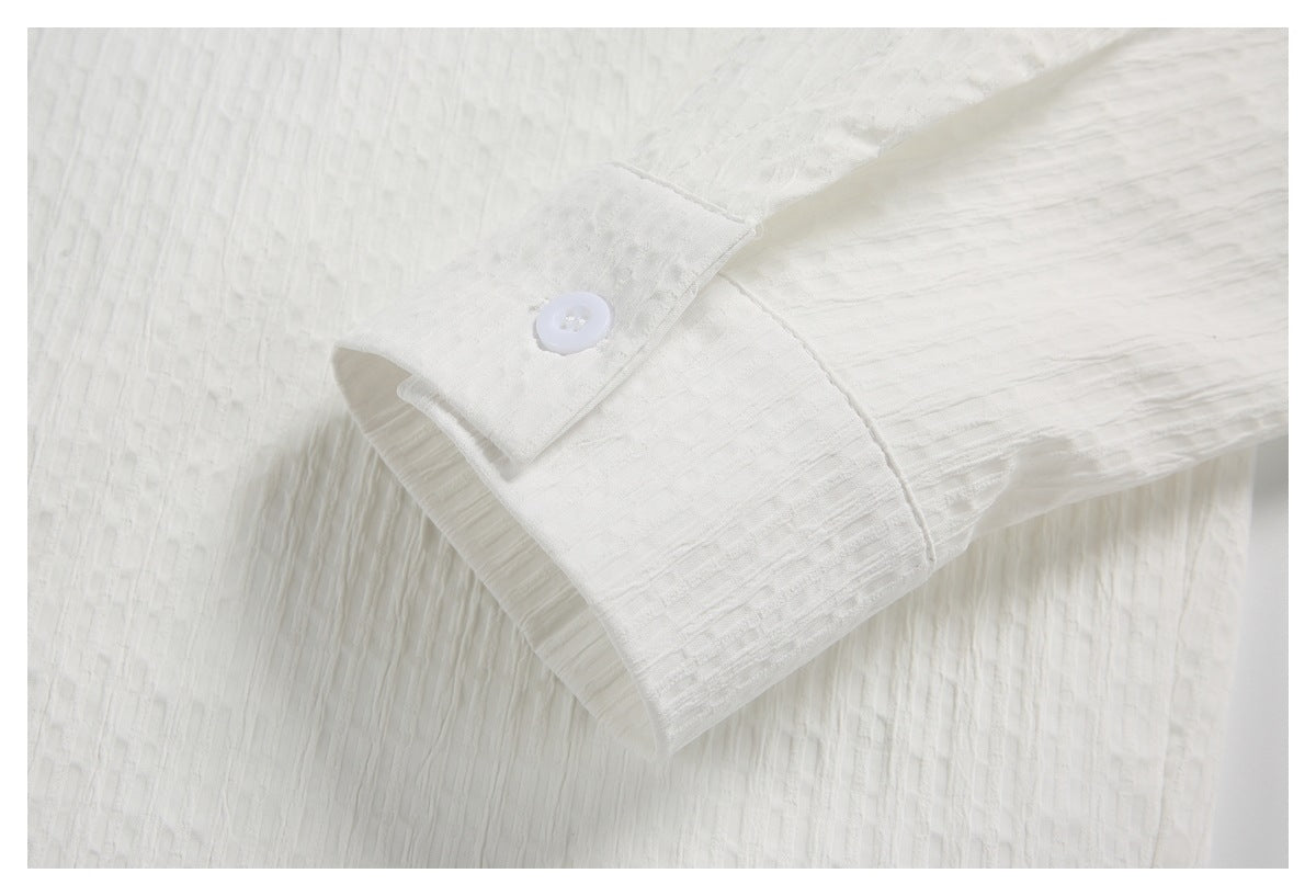 Close-up of the white shirt's buttoned cuff and textured sleeve.