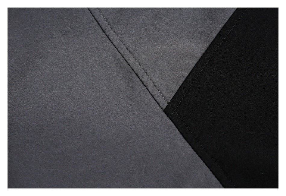 Close-up of charcoal gray and black garment panels meeting at a stitched seam.