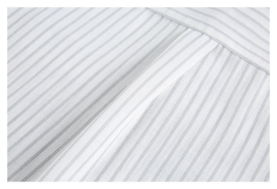 Close-up of a white striped garment showing a curved seam and overlapping fabric panels.