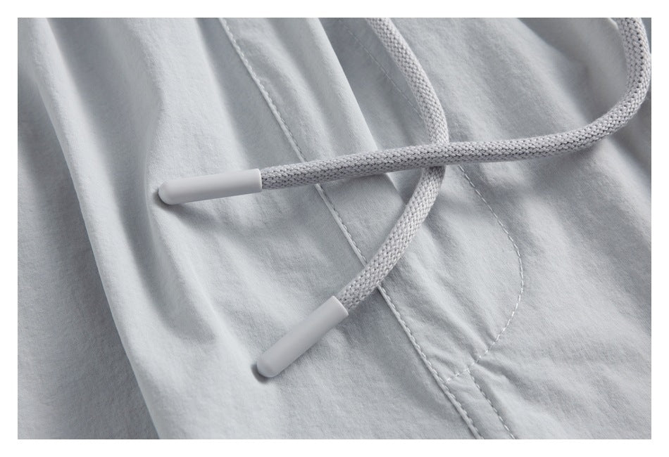 Close-up of the light gray shorts’ braided drawstrings and stitched front panel.