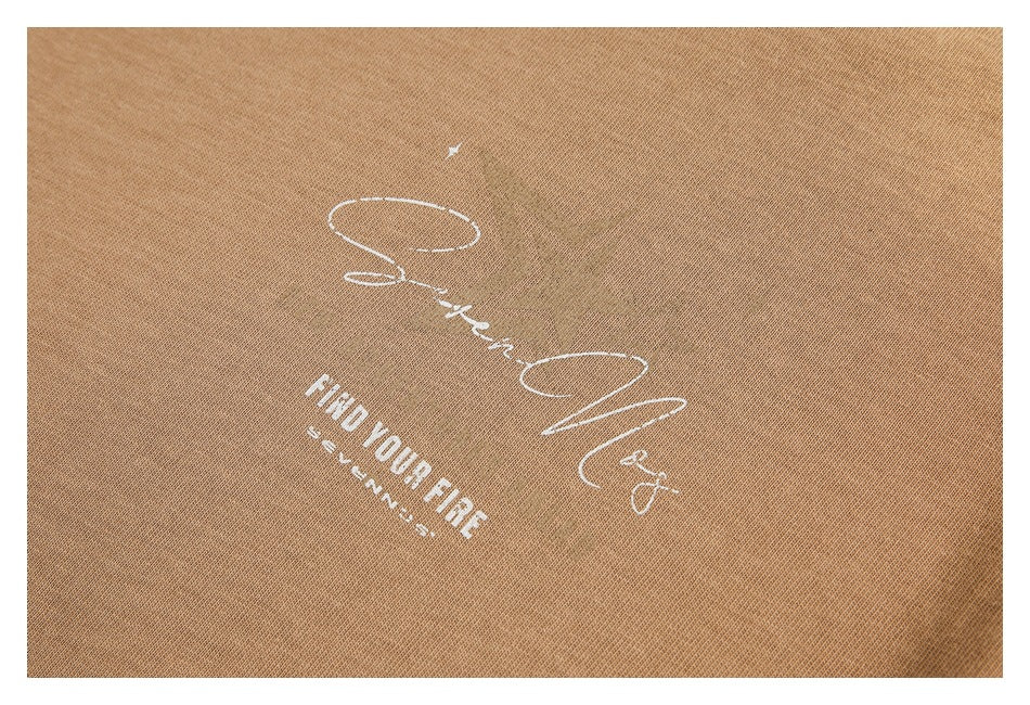 Close-up of a white script and text graphic printed on camel-brown T-shirt fabric.
