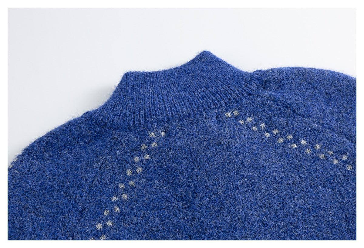 Close-up of a blue knitted sweater collar and shoulder with small light-colored star-like motifs.