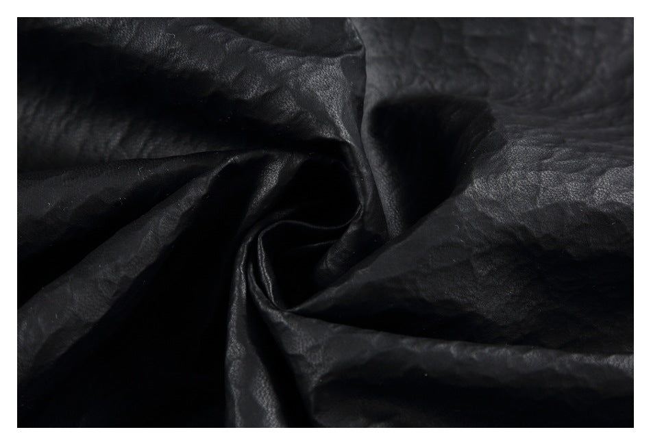 Close-up of black textured garment material gathered into folds.