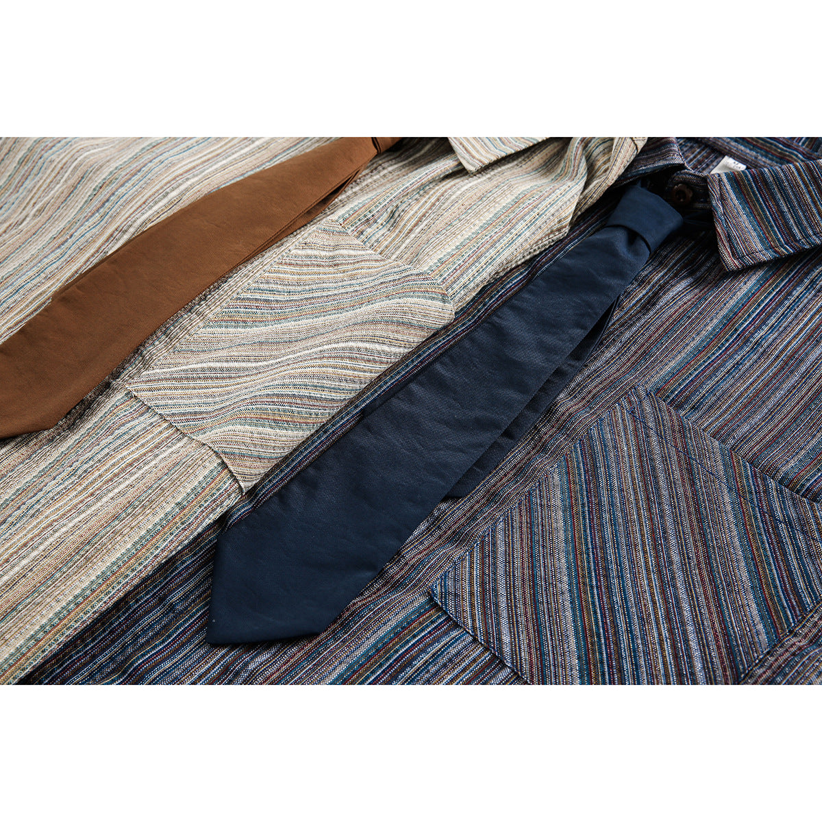Close-up of light and dark striped shirts with brown and navy ties and chest pockets.