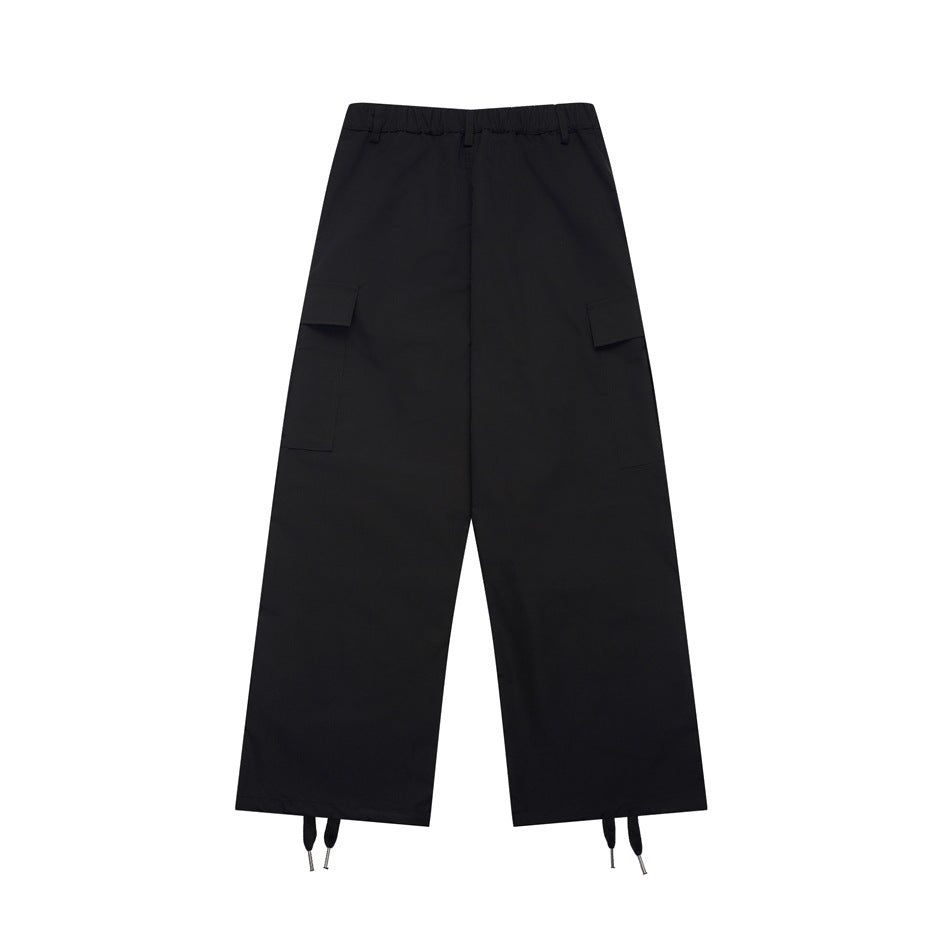 Front view of black wide-leg cargo pants with an elastic waistband, flap pockets and adjustable ankle cords.