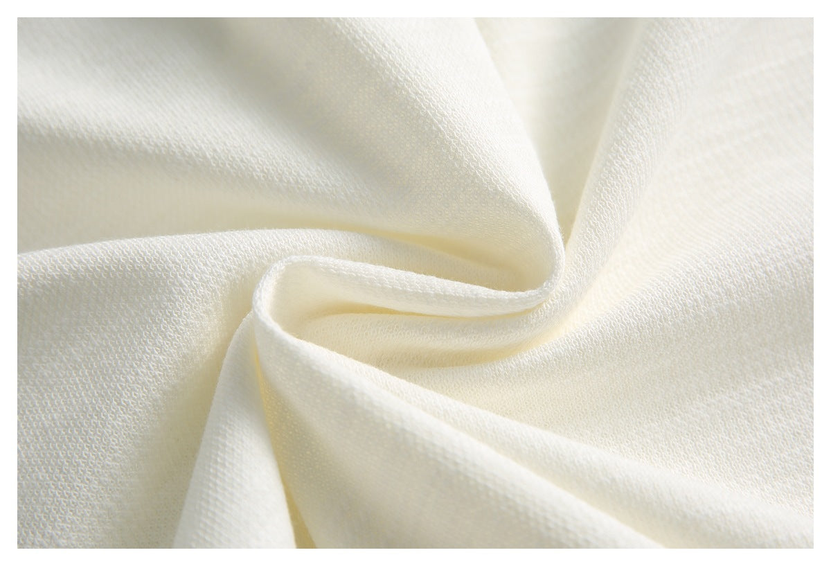 Close-up of softly folded ivory-white fabric with a fine textured weave.