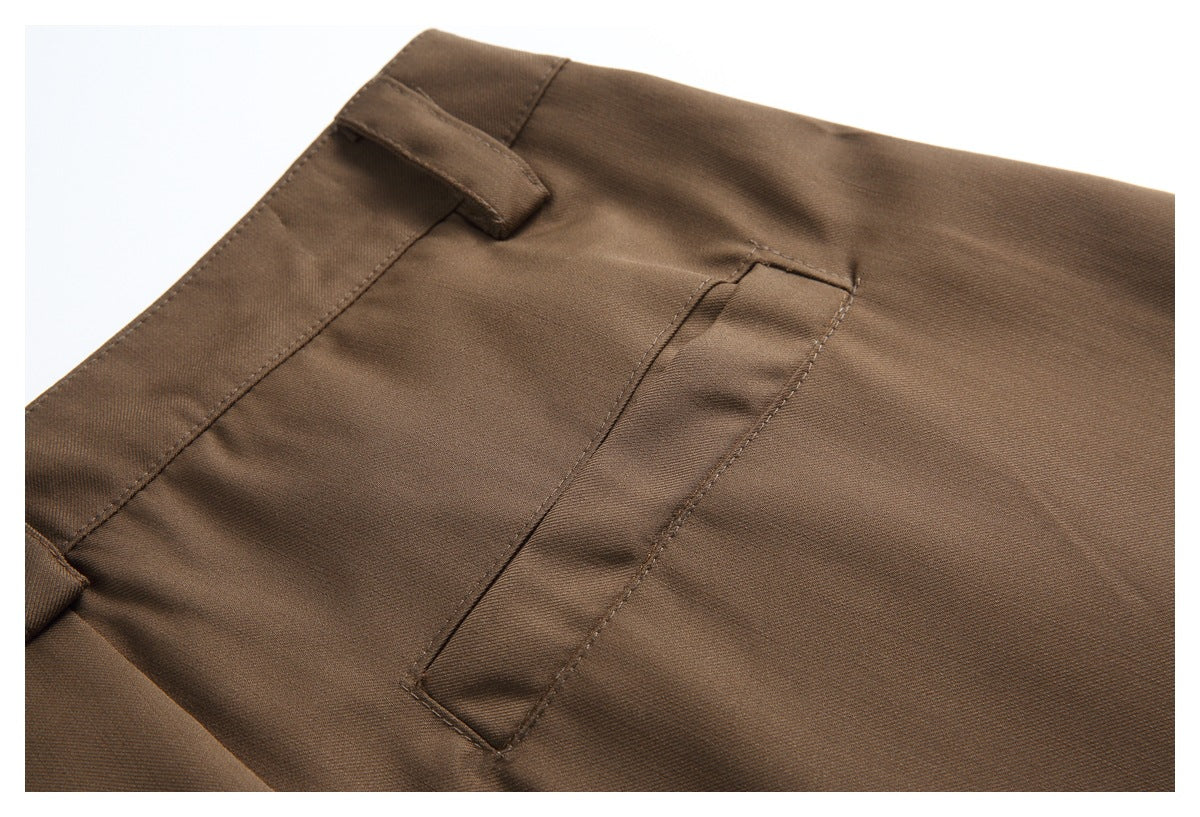 Close-up of brown trousers showing a belt loop, waistband seam, and narrow pocket detail.