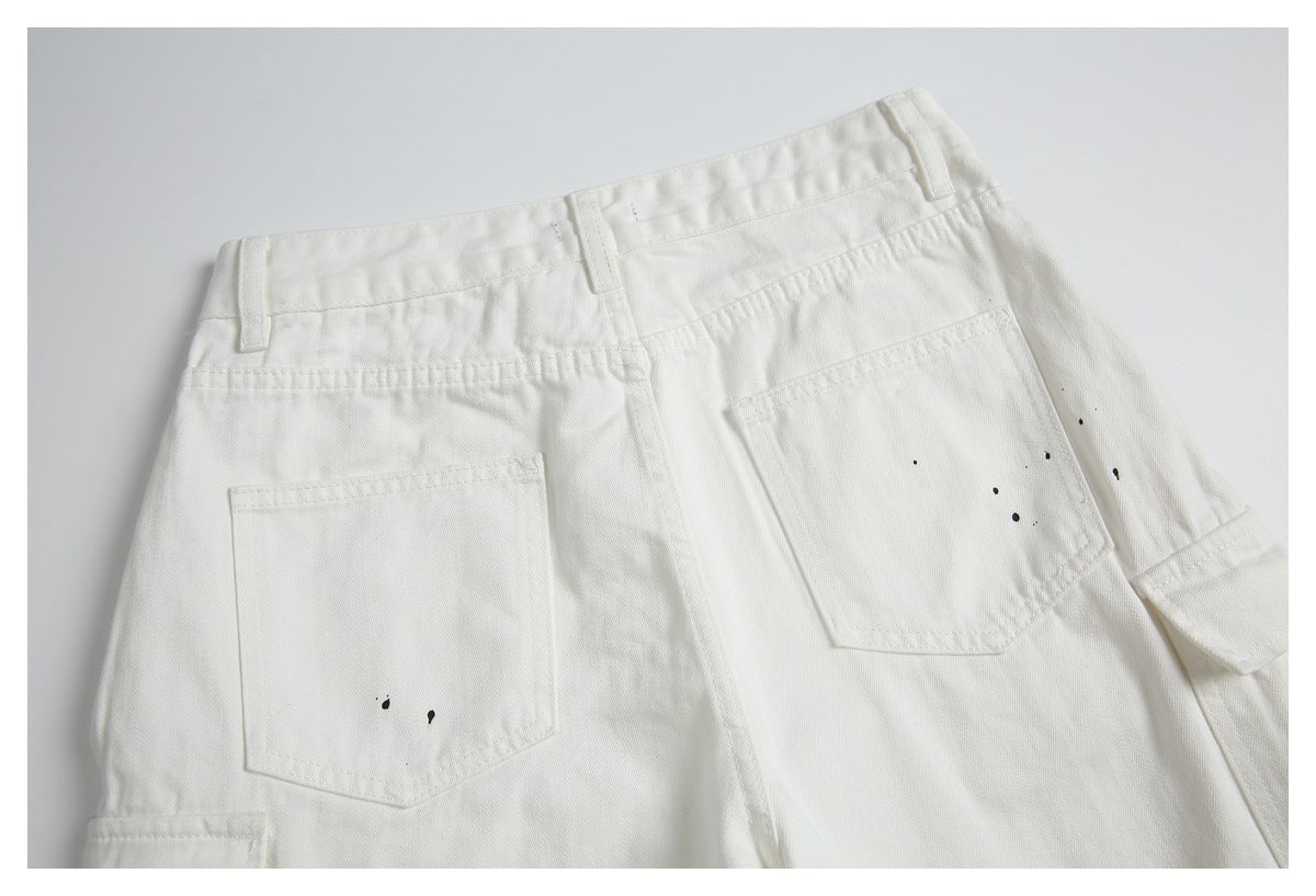 Rear view of off-white shorts with belt loops, two back pockets, and scattered black paint-like marks.