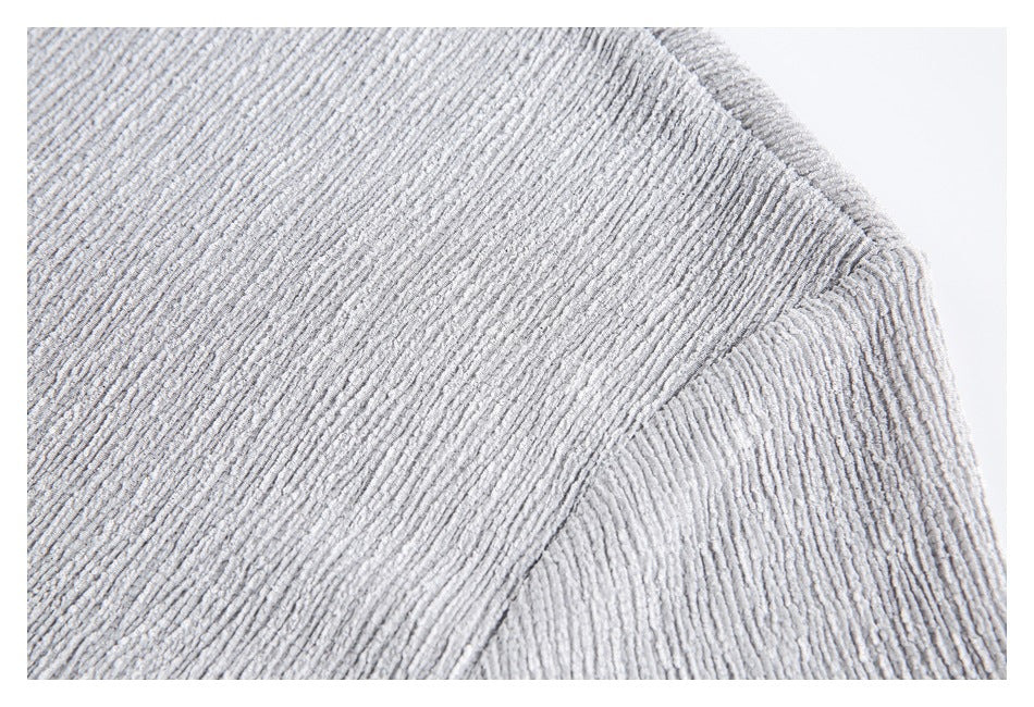 Close-up of the shoulder seam and textured fabric on a light gray top.