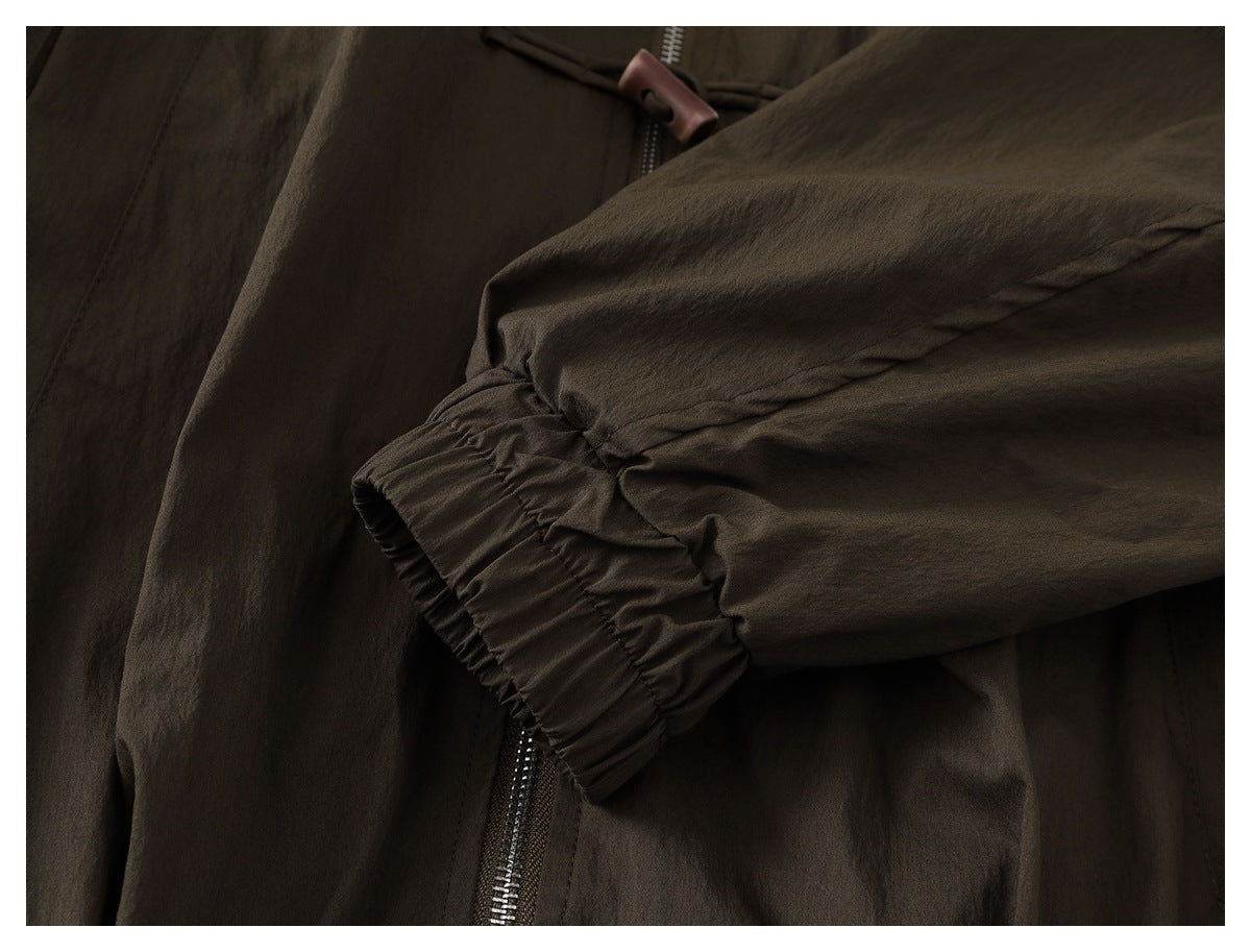 Close-up of a dark olive-brown jacket sleeve with a gathered elastic cuff and part of the front zipper.