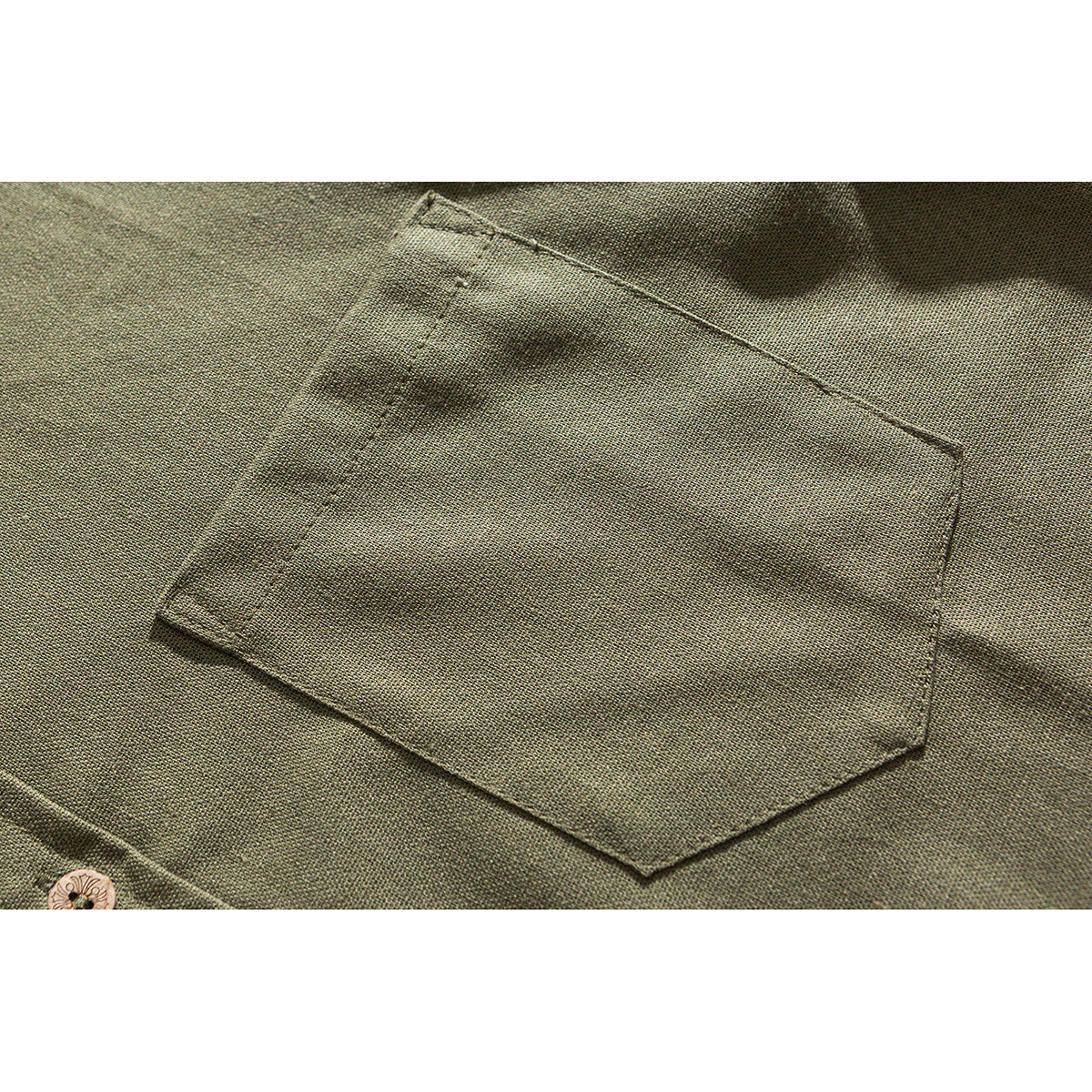 Close-up of the olive shirt's stitched chest pocket and a button near the lower edge.