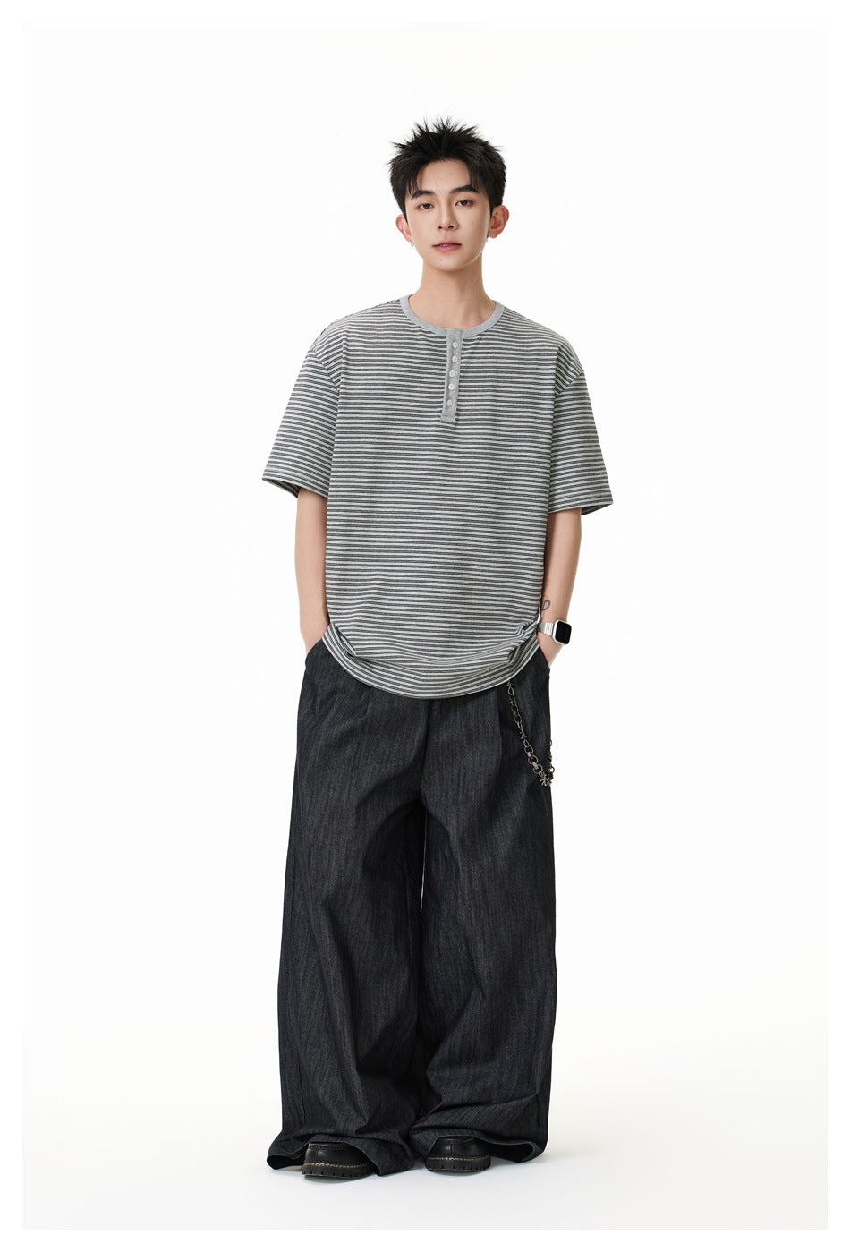 Full-length view of model in gray striped Henley T-shirt with wide-leg dark denim pants and chain