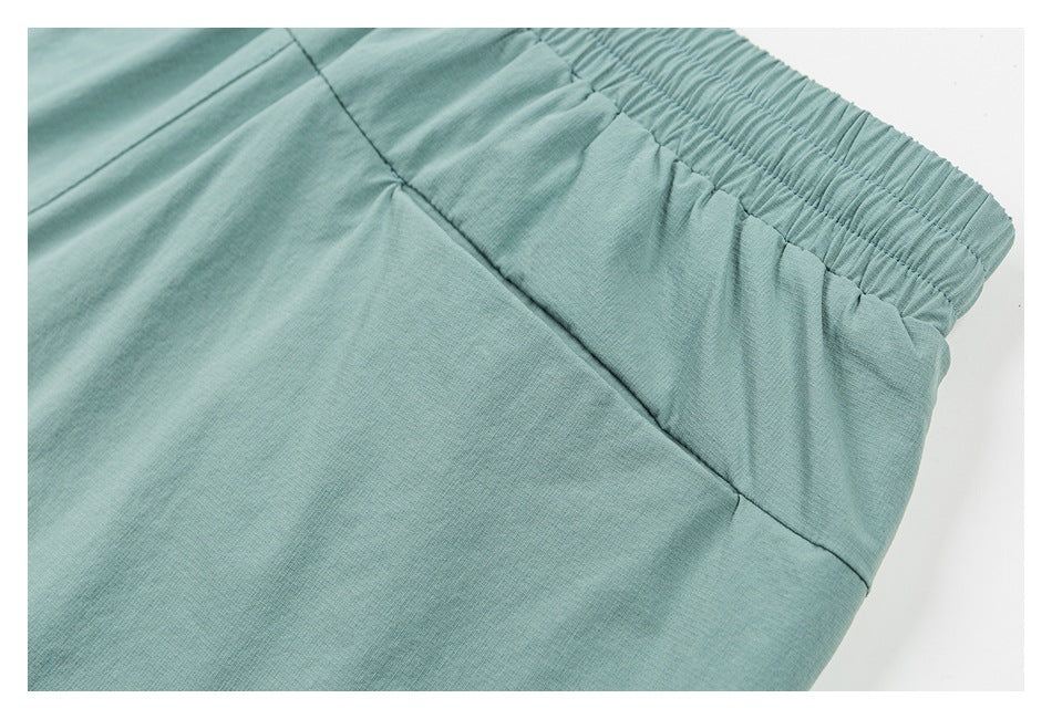 Close-up of mint-green shorts showing the gathered waistband and a diagonal seam.